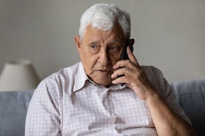 An older man using a phone on his sofa
